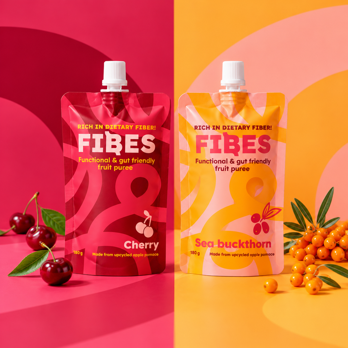 Two stand-up pouches of FIBES functional and gut friendly fruit puree are displayed side-by-side on a split pink and orange background. The left pouch is Cherry flavor with a dark red design, and the right pouch is Sea buckthorn flavor with a yellow-orange design.